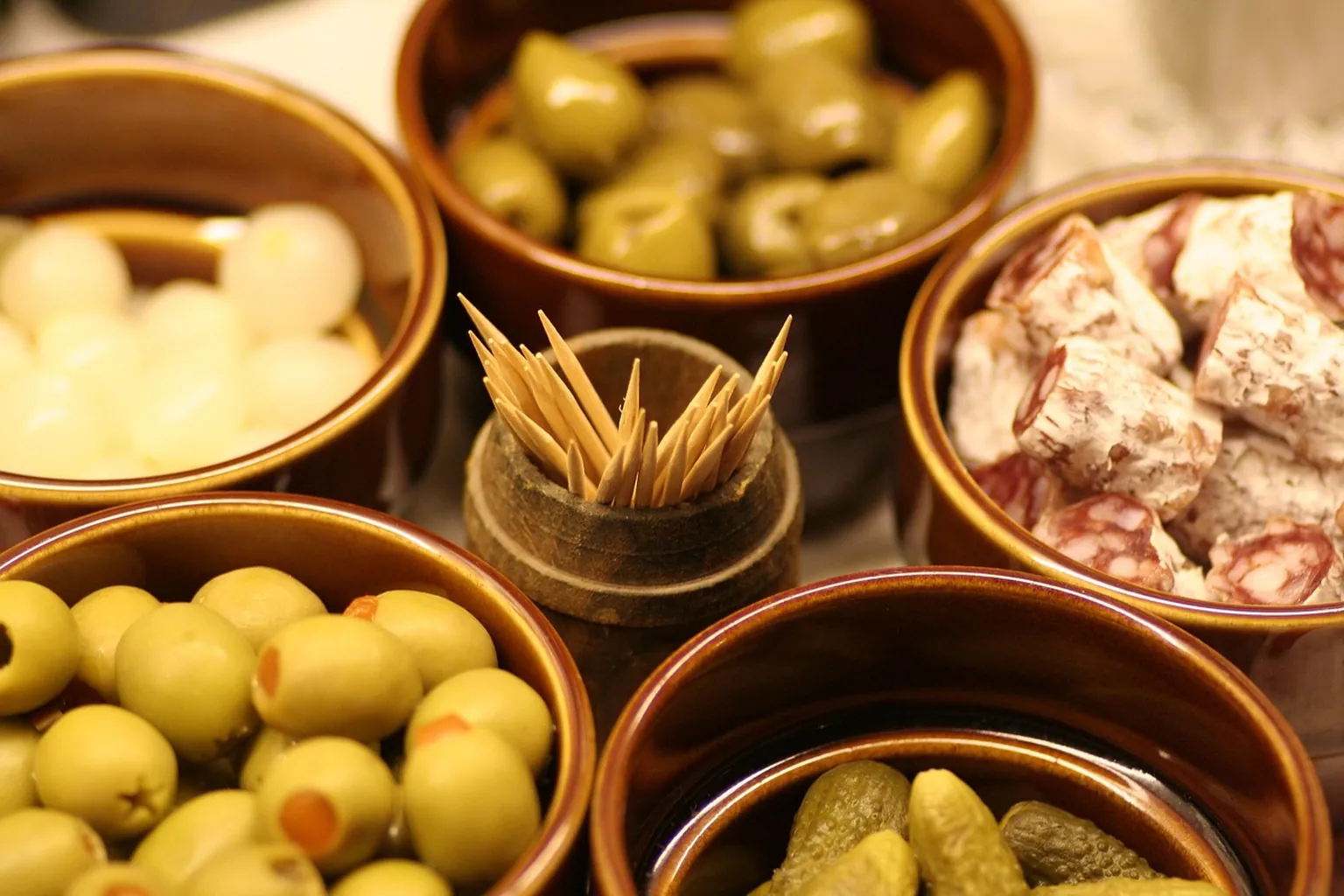Small bowls of olives, cured meat, cheese and pickles
